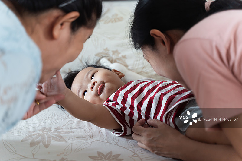 可爱的亚洲宝宝和妈妈、奶奶在床上玩耍图片素材
