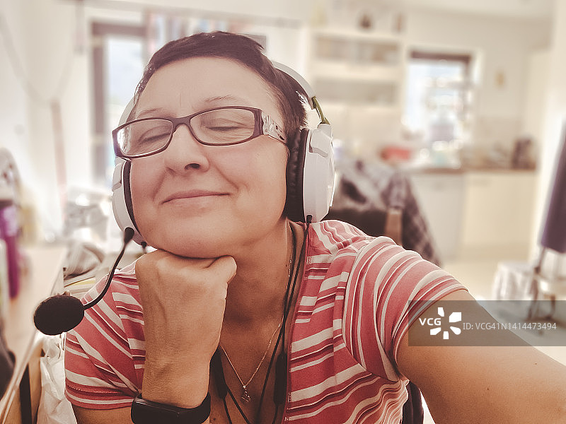在家里听音乐，脸上带着梦幻般快乐表情的快乐女人肖像，她闭着眼睛图片素材