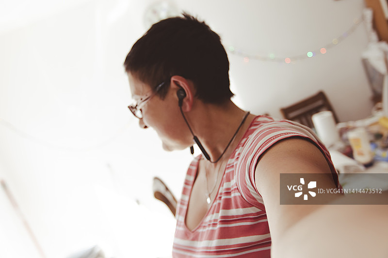 在厨房里听音乐跳舞的女人，背景模糊图片素材