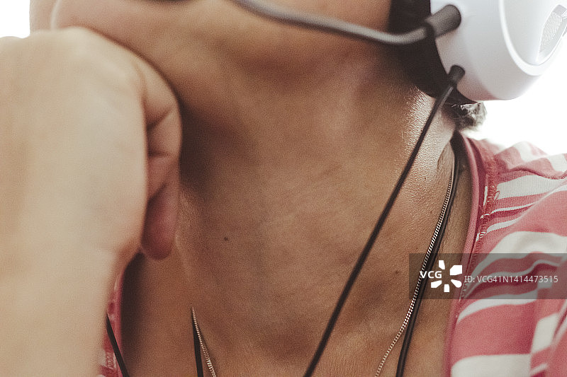 手托下巴，戴着耳机听音乐的人的肖像，晒黑的皮肤特写图片素材