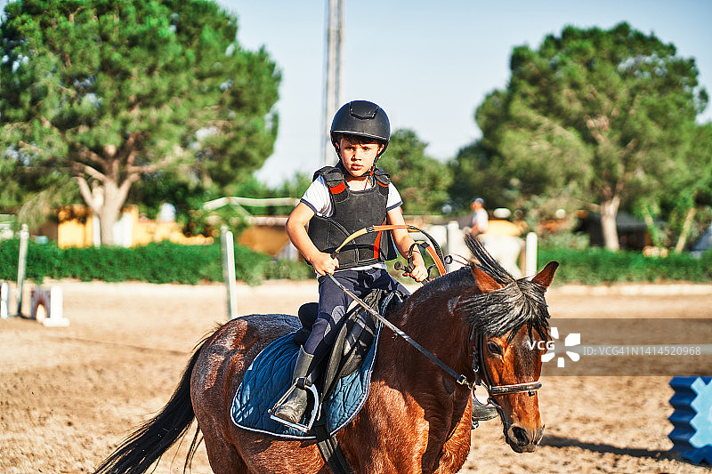 男孩在围场里骑马图片素材