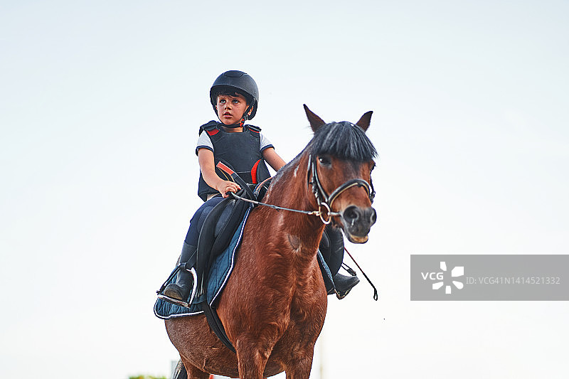 男孩在灰色天空下骑马图片素材
