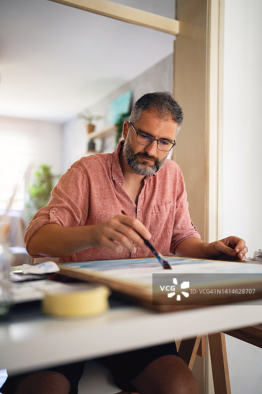用颜料在画布上绘画的白人男艺术家图片素材