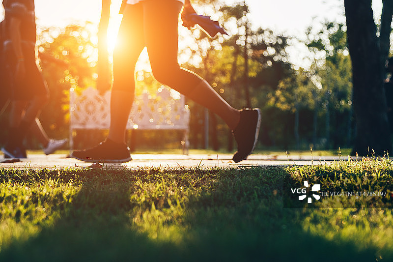 城市公园日落时在道路上跑步的活力女性。健身和锻炼健康概念。柔焦复古图片素材