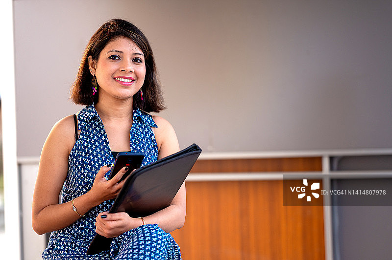 年轻女子在市中心公交车站使用智能手机等公交车或出租车图片素材