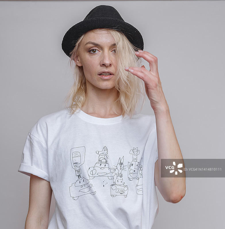 戴着猪肉馅饼帽的金发成年女人，影棚灰色背景图片素材