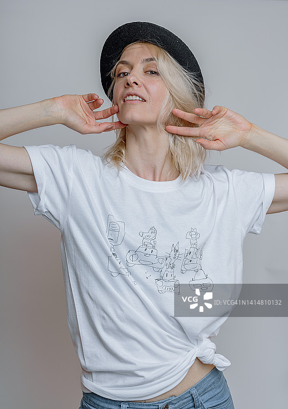 戴着猪肉馅饼帽的金发成年女人，影棚灰色背景图片素材