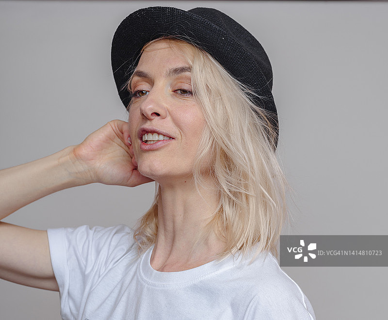 戴着猪肉馅饼帽的金发成年女人，影棚灰色背景图片素材