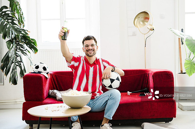 年轻男人在家看电视时欢呼图片素材