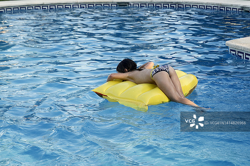 女孩躺在泳池漂浮筏上图片素材