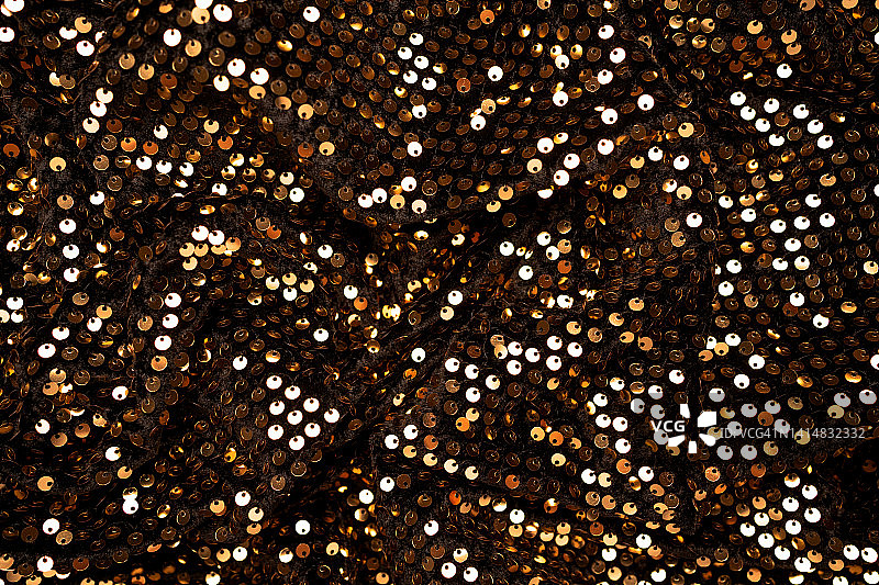 黑色丝绒上的金色亮片特写图片素材