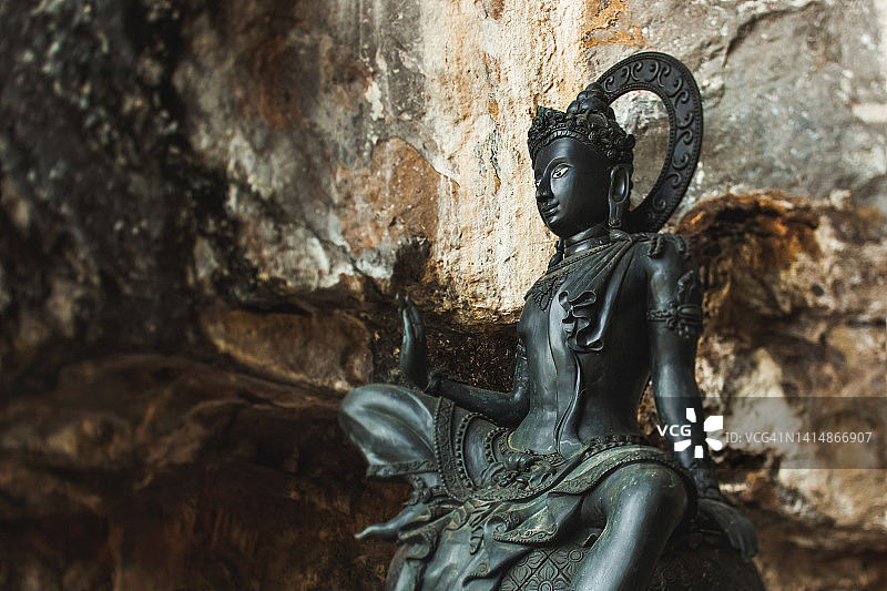 洞穴寺庙中的泰国宗教黑色金属雕像。佛教中的神圣精神。图片素材
