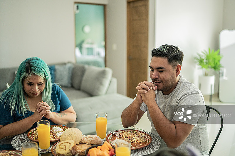 已婚夫妇在家中午餐前祈祷图片素材
