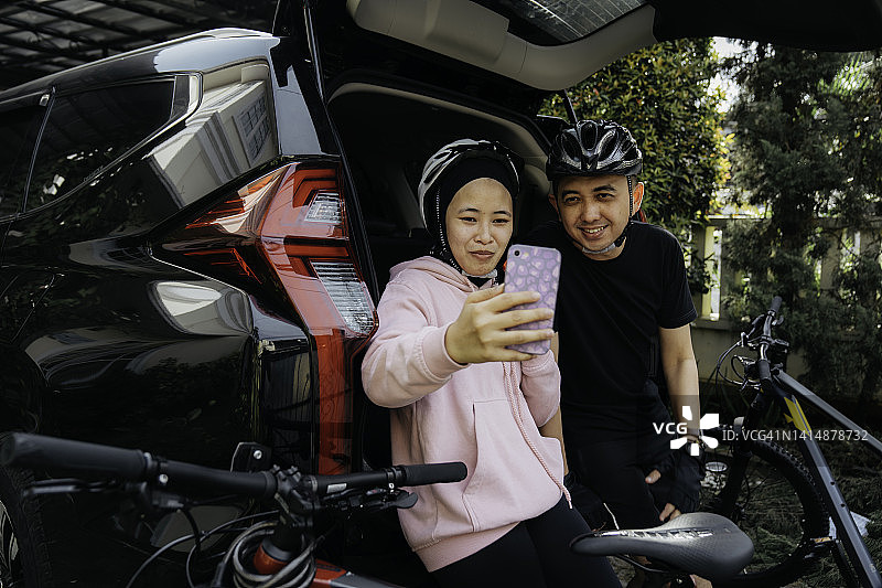 年轻的穆斯林夫妇打电话给朋友准备去骑自行车图片素材