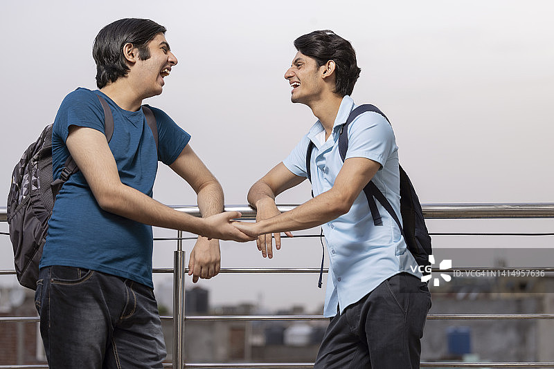 两个青少年朋友站在栏杆旁聊天图片素材