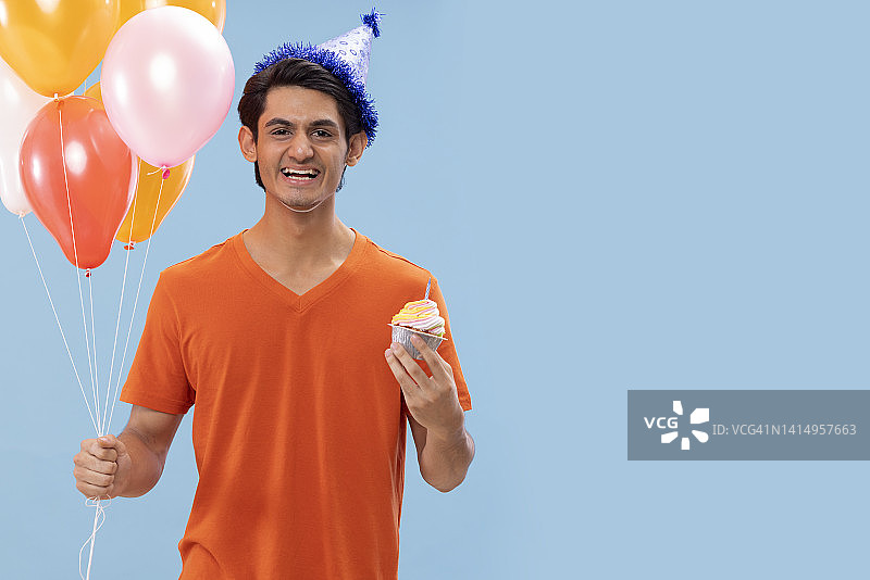 戴生日帽的快乐男孩手捧气球和蛋糕的肖像图片素材
