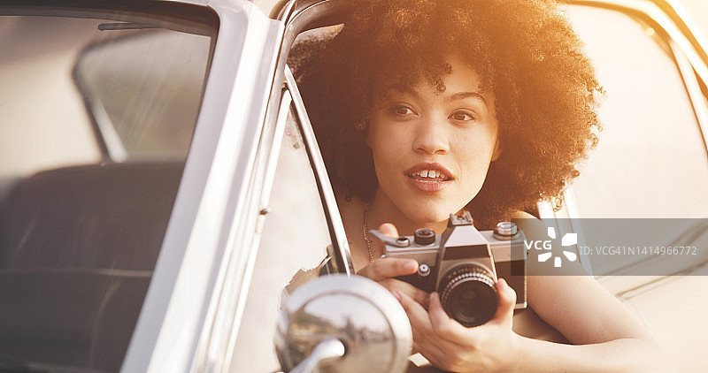 年轻女子在公路旅行中用相机拍照，享受旅行、旅游和自由。女摄影师在旅途中观光时拍照图片素材