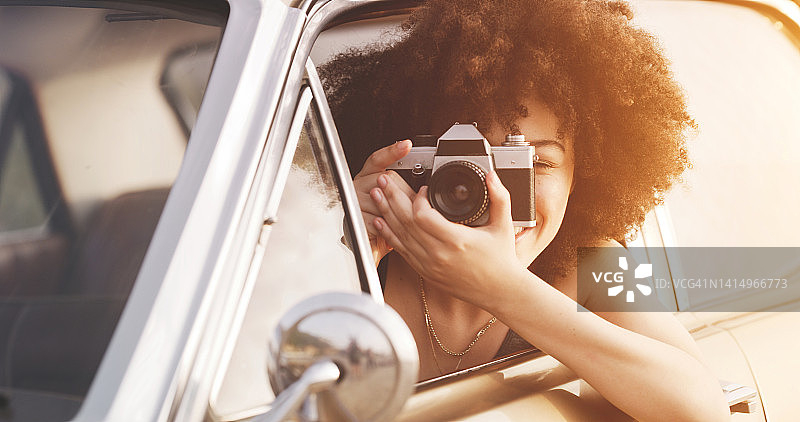 年轻女子在公路旅行中用相机拍照，享受旅行、旅游和自由。女摄影师在旅途中观光时拍照图片素材
