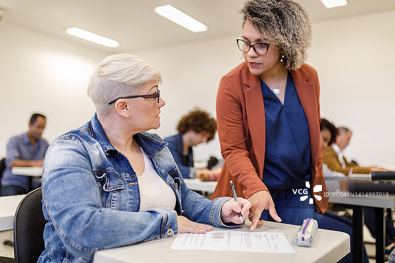教授向短发学生讲解考试题目图片素材