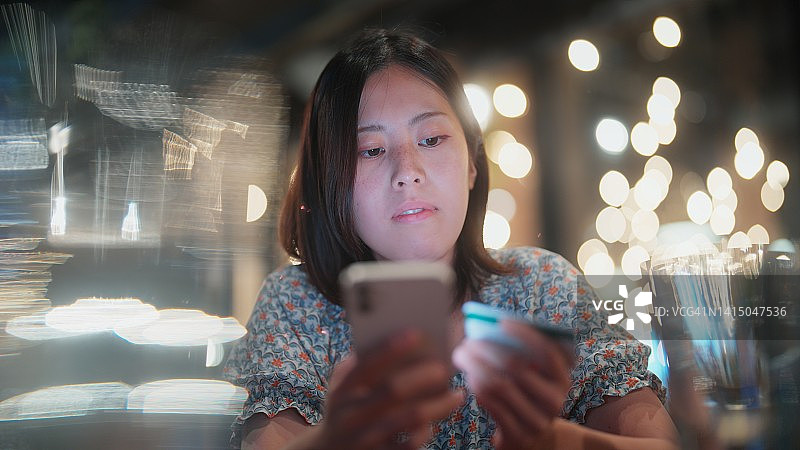 年轻女子在咖啡馆使用信用卡和智能手机进行网上购物或支付图片素材