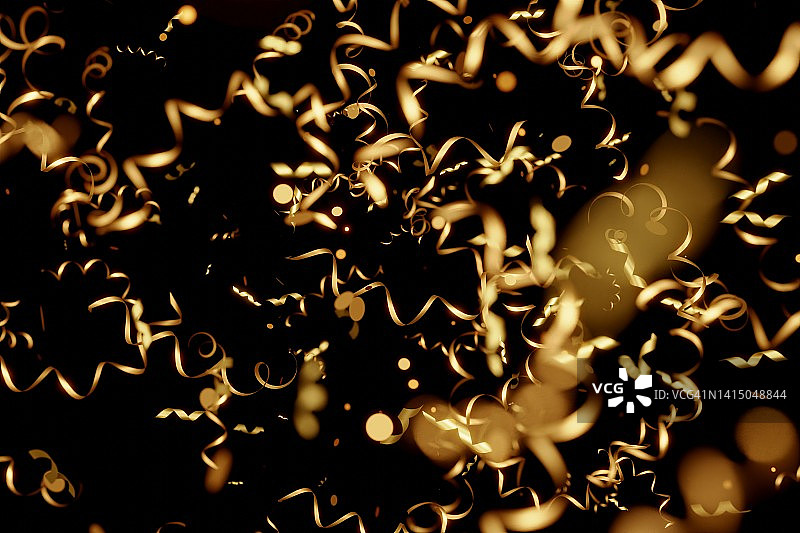 黑色背景上的金色蛇形彩带纸屑。节日圣诞背景。三维插图图片素材