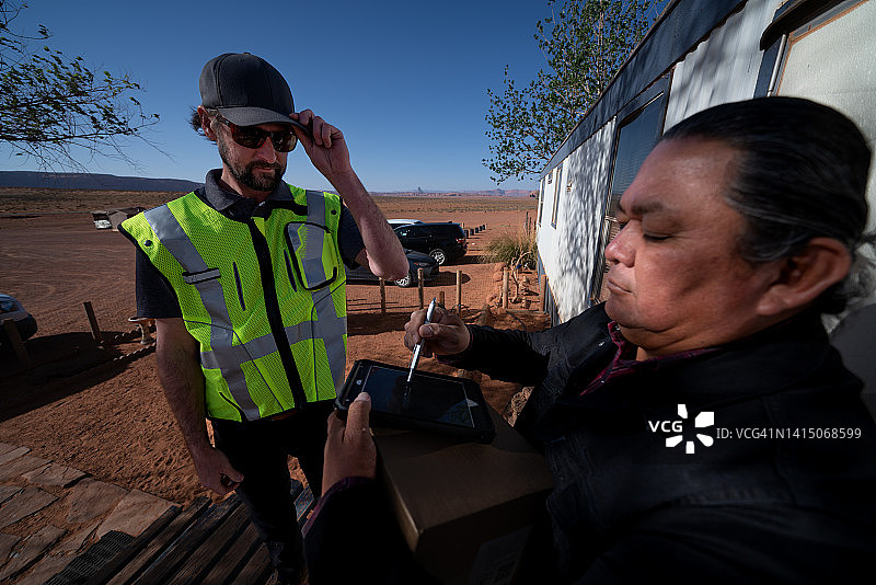 男子在小镇的组合房屋里给老年男子送包裹图片素材