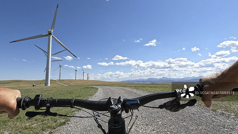 骑电动自行车驶向一排风力涡轮机的视角图片素材