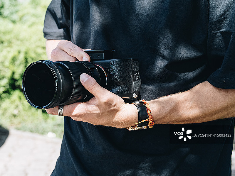 摄影师在户外手持单反相机的细节图片素材