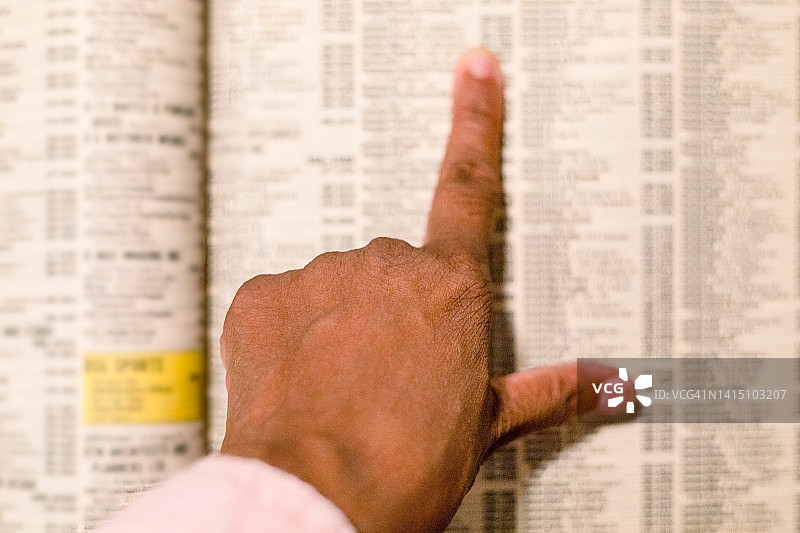 黑人女性在传统纸质电话簿中查找电话号码图片素材