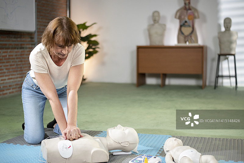 这位女士正在对人体模型进行心肺复苏术图片素材