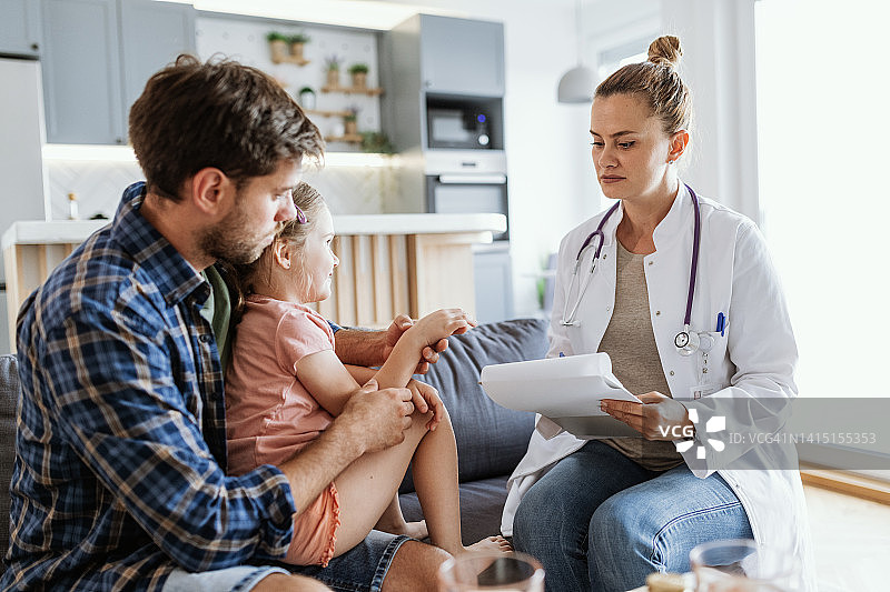 医生在家拜访生病的小女孩。女医生用听诊器和手术服检查女孩的健康状况图片素材