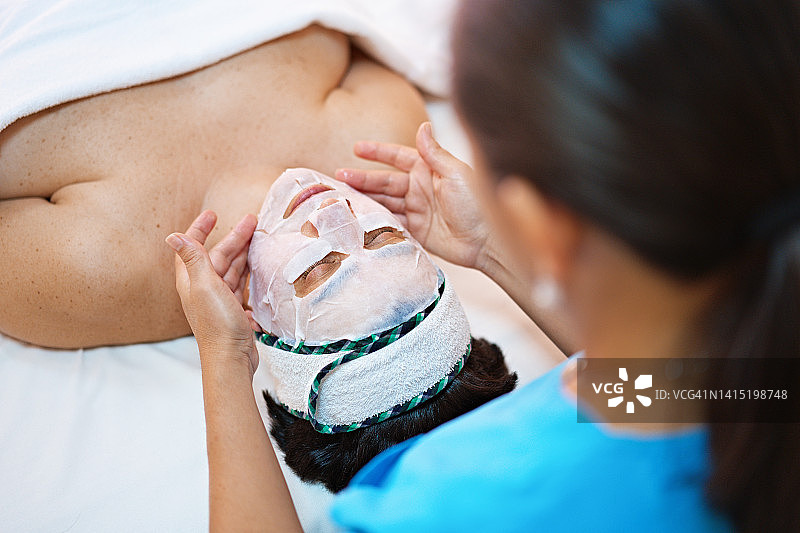 美容师给女人脸上涂抹净化面膜图片素材