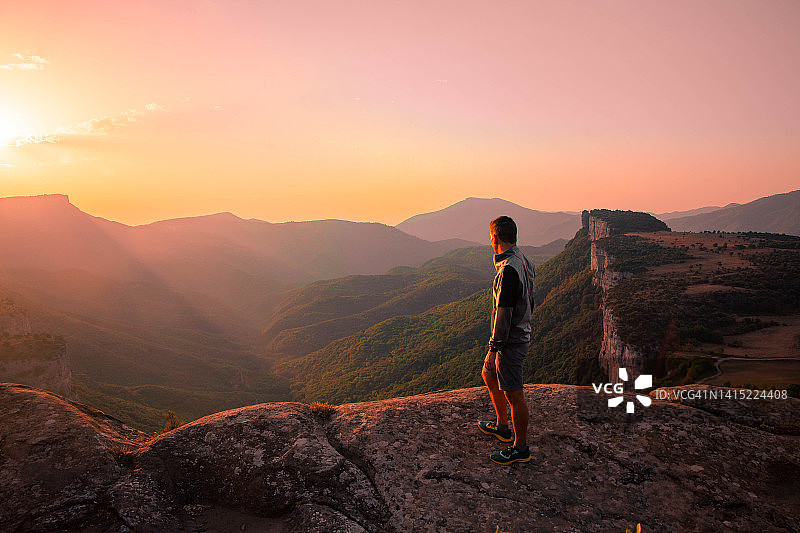 男子从岩石 viewpoint 沉思着加泰罗尼亚 Collsacabra 山脉雄伟的日出图片素材