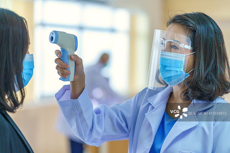 使用红外线数字温度计测量体温，以进行预防和安全测量图片素材