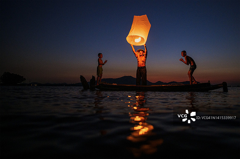 在水灯节期间，木船上带着浮动灯的渔民图片素材