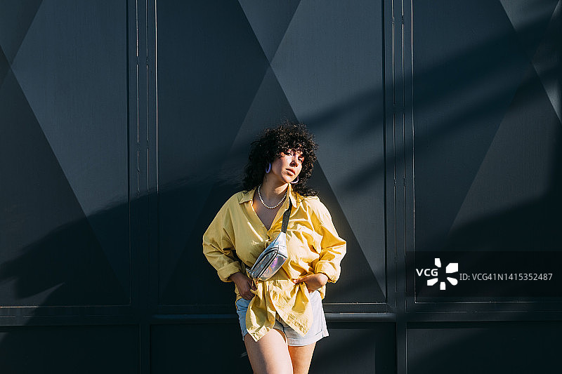 自信的女人在灰色的墙前带着腰包图片素材