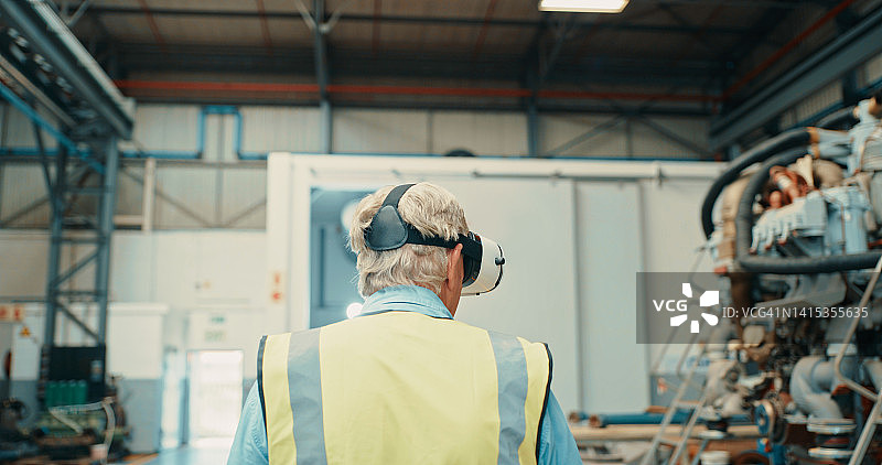 机械工程师在工厂佩戴3D虚拟现实头显进行创新设计，探索未来在线虚拟形象元宇宙。制造商仓库经理的后视图图片素材