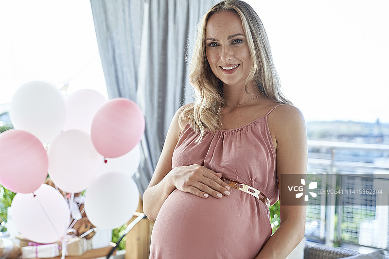 面带微笑的孕妇在迎婴派对上穿着粉色连衣裙图片素材