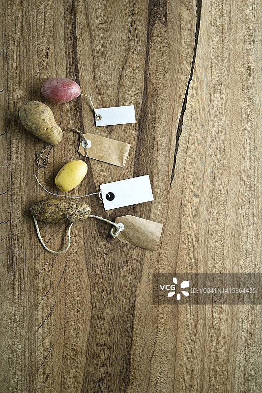 不同品种的带标签的土豆平铺在木质背景上的影棚照片图片素材