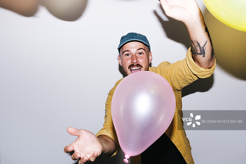 在家中墙前玩气球的快乐男人图片素材