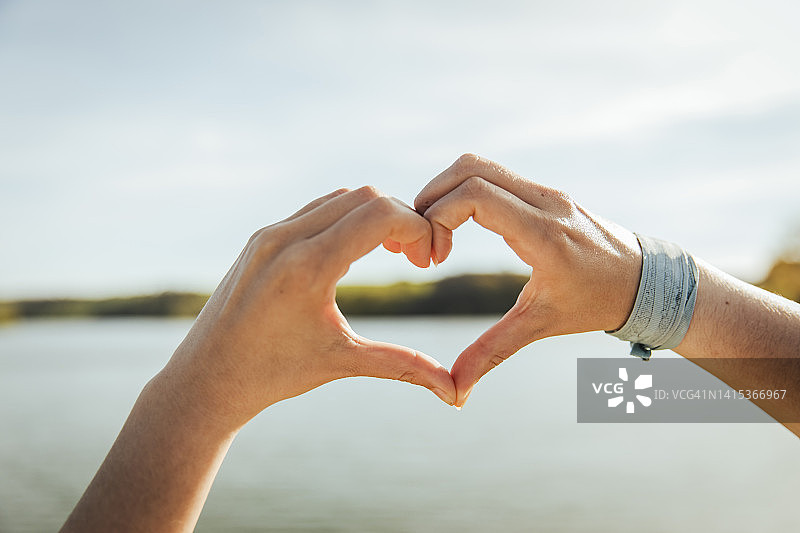 年轻女人在晴朗的一天比心图片素材