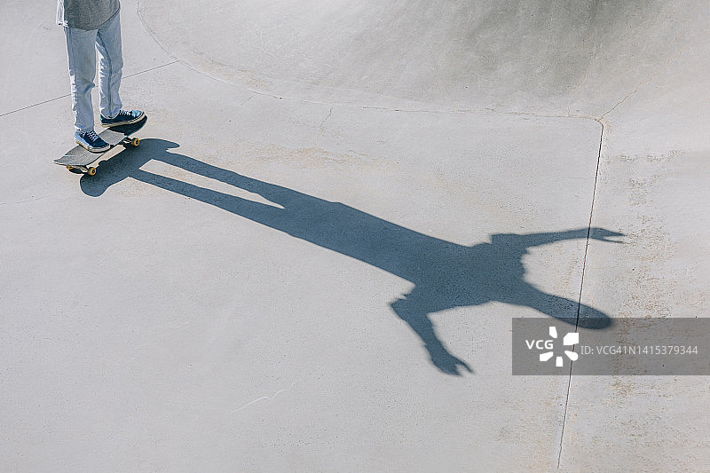 阳光明媚的日子里带着滑板的男人的影子图片素材