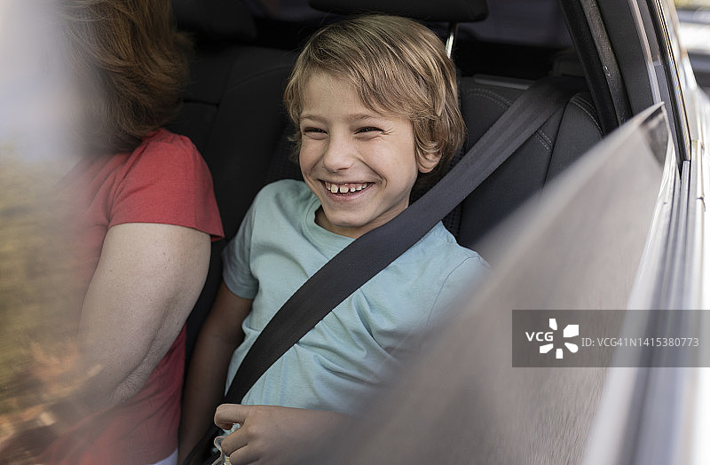 微笑的男孩坐在车里，奶奶在旁边图片素材