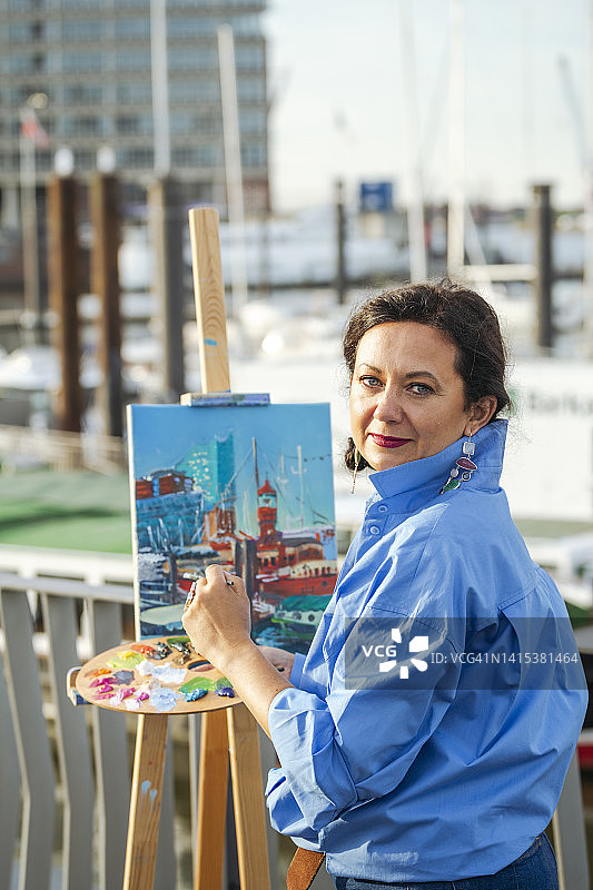 微笑的艺术家在海港用调色板绘画图片素材