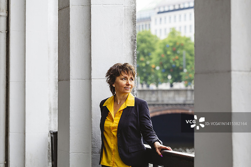 站在柱子间的栏杆旁的沉思的女人图片素材