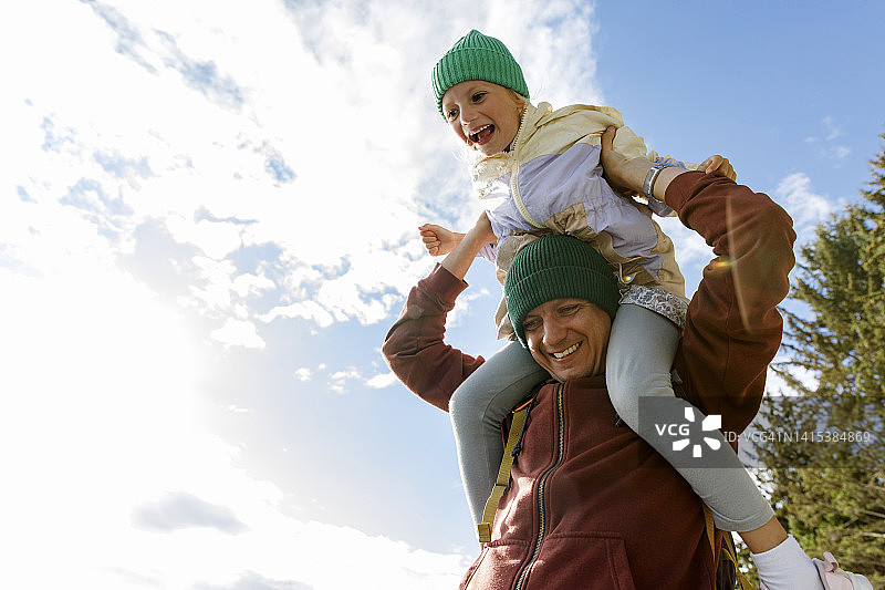 快乐的父亲和坐在肩膀上的女儿玩耍图片素材
