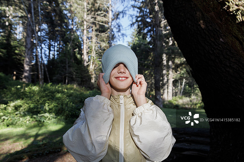 戴针织帽的女孩在阳光明媚的森林里图片素材