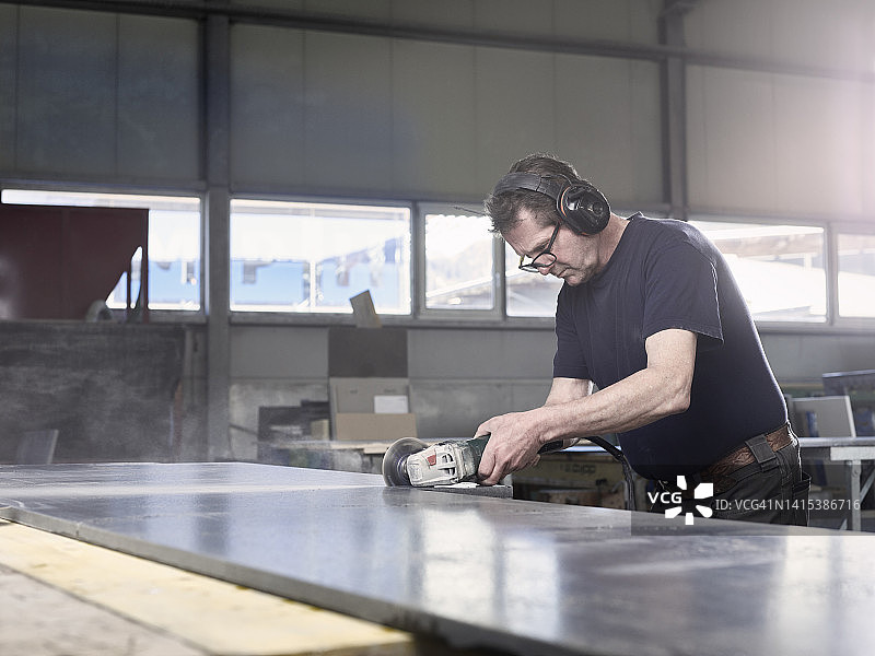 石匠在车间用研磨机切割大理石板图片素材