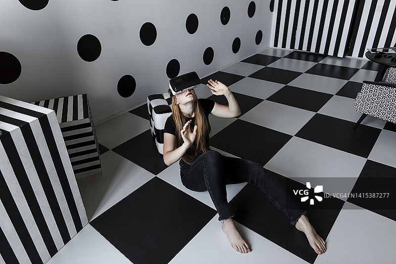 戴着VR头显坐在格子地板上的女孩图片素材