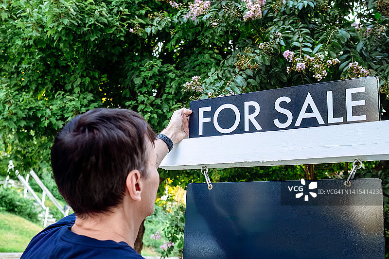 房地产经纪人在前院调整出售标志图片素材